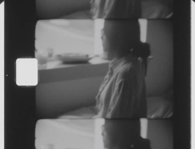 Young woman sitting on the bed next to a window caught on vintage film