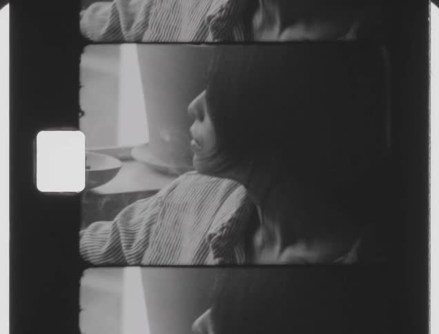 Woman smoking in the bed next to a window caught on vintage film