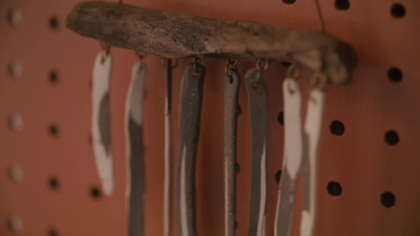 A wooden pegboard with hooks holds a set of hanging decorations