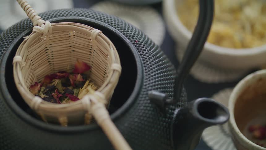 Woman hand putting spices into a cup on top of a kettle