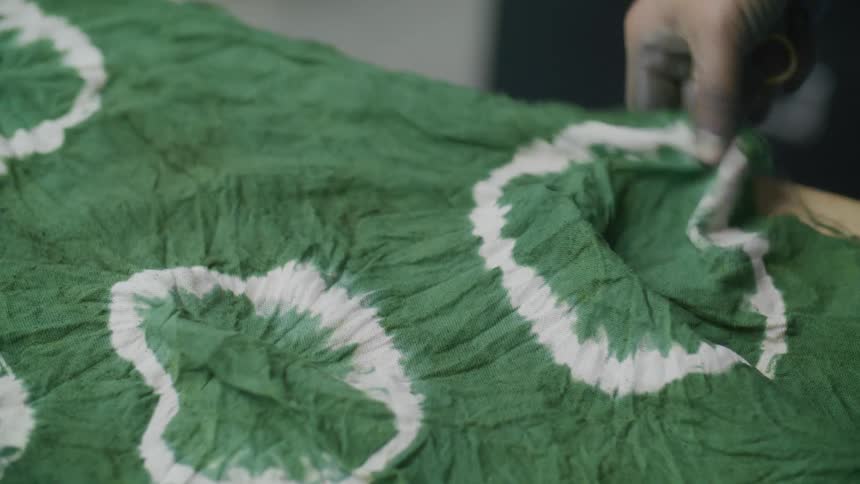Womans hand opening a green tablecloth and placing it on the table