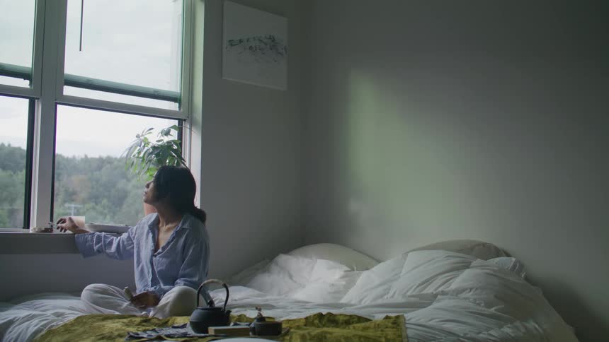 A woman sitting in bed smoking a cigarette