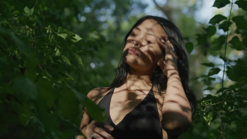 A young woman contemplates while standing in a forest