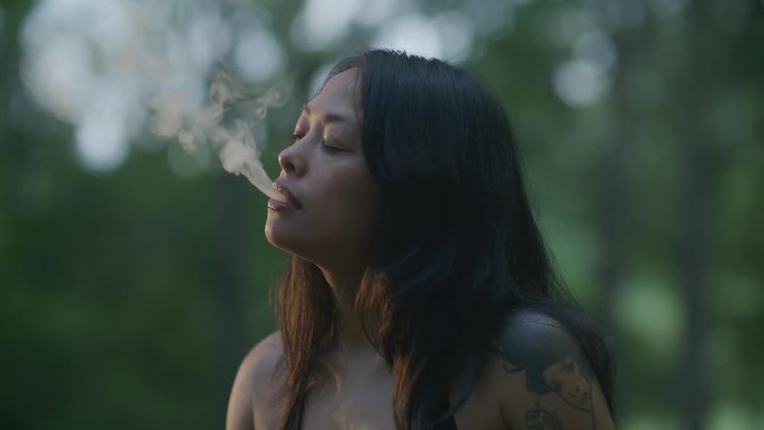 A tattooed woman is smoking a cigarette