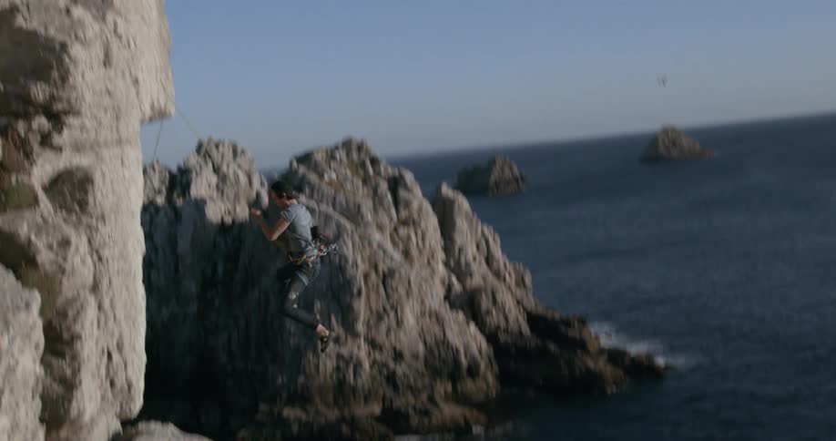 A person who was climbing a rock jumps off it while hanging from the rope