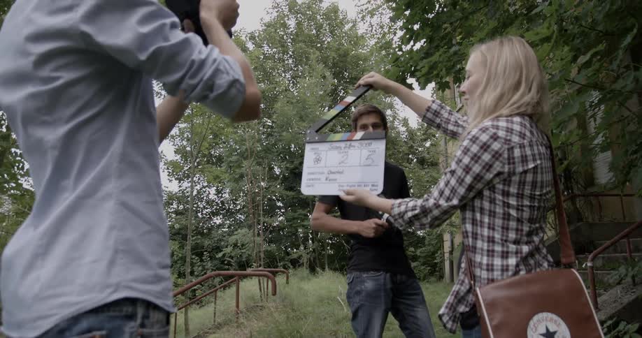 A crew begins to film a scene bear a building