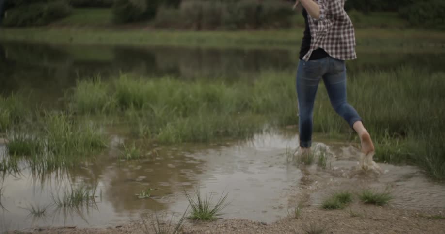 A woman in a plaid skirt runs through a puddle