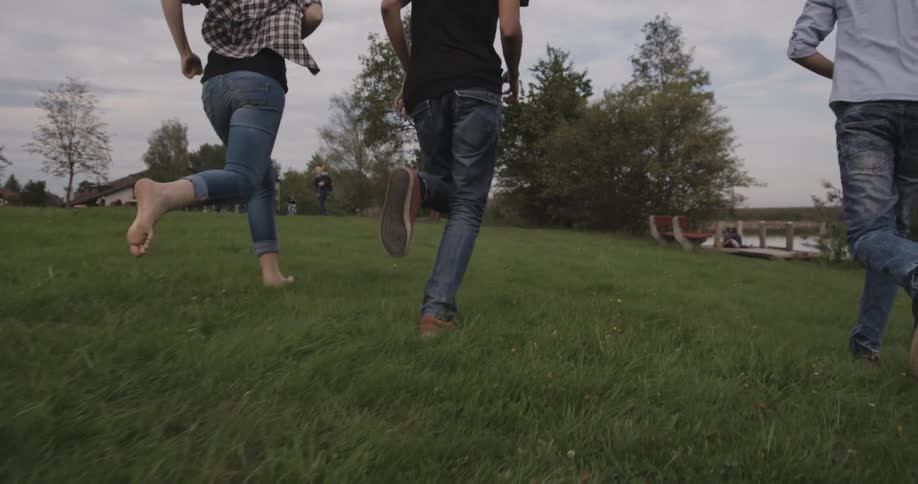 Three people a running through a grassy field