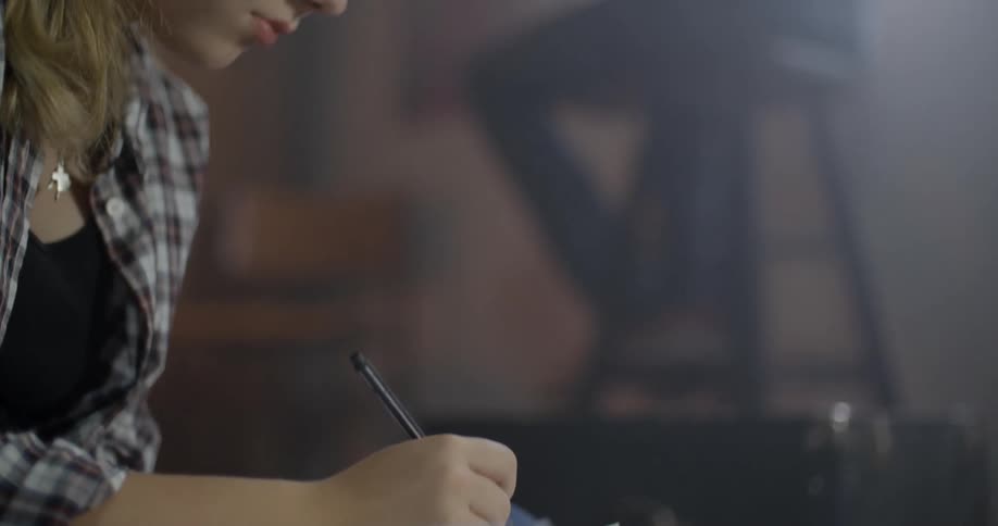 A woman sits and writes in a notebook