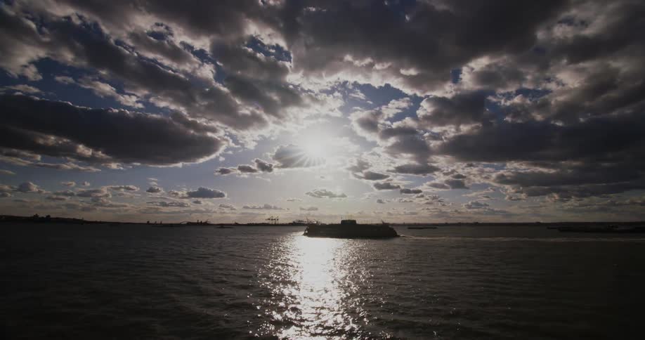 A boat travels across the water on a partly cloudy day