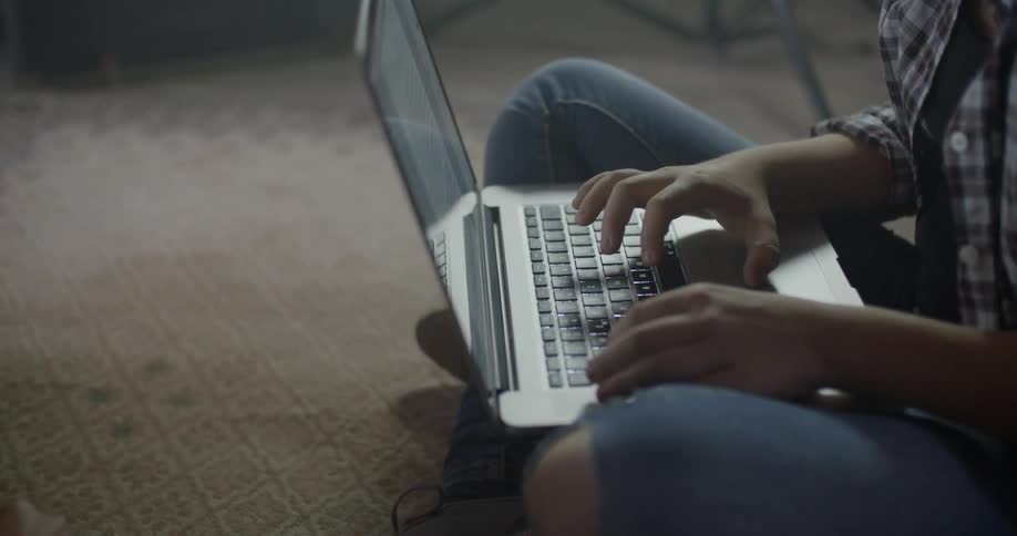A person is sitting on the ground using a laptop