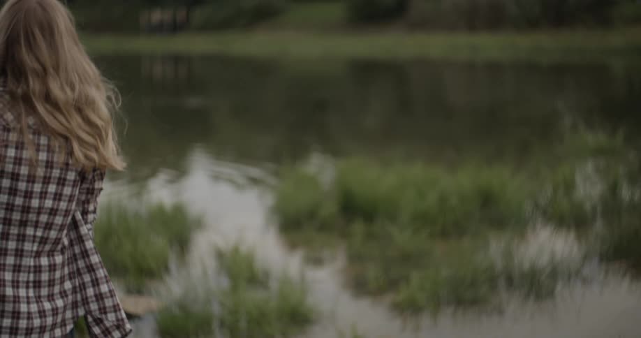 A woman skips a stone across a pond