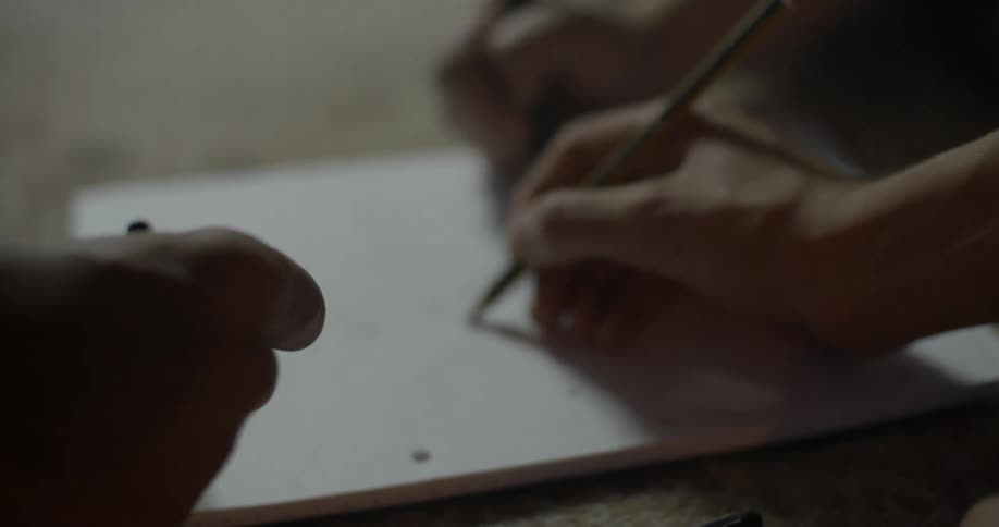 Three people sit on the floor writing in a notebook