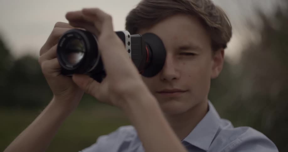 A young man adjusts a zoom lens
