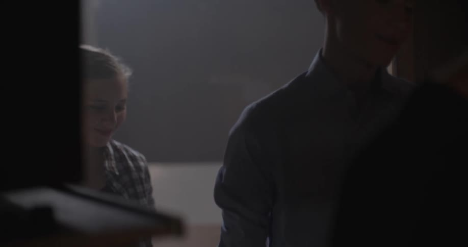 Three young people walk through a dim and hazy room