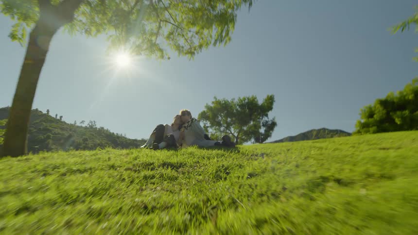 A man and a woman lean against each other under a tree