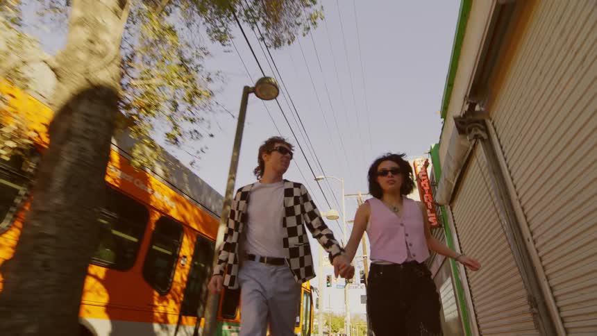 Man and woman running on the sidewalk hand in hand