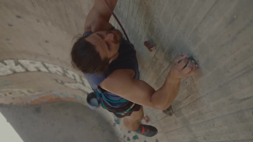 A man climbs a climbing wall during the day