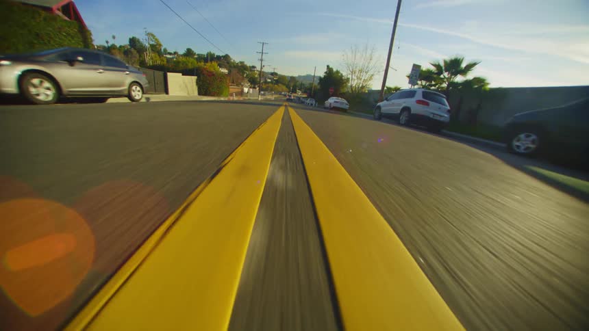 Pov driving along double yellow line on pavement car lined street