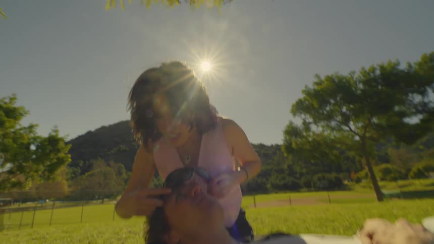 A man and a woman goof around with a pair of sunglasses