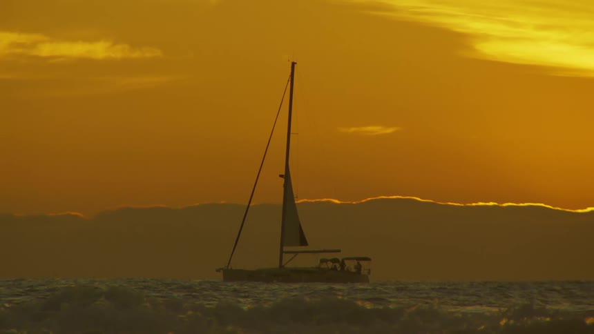 A sailboat with two passengers bobs on waves