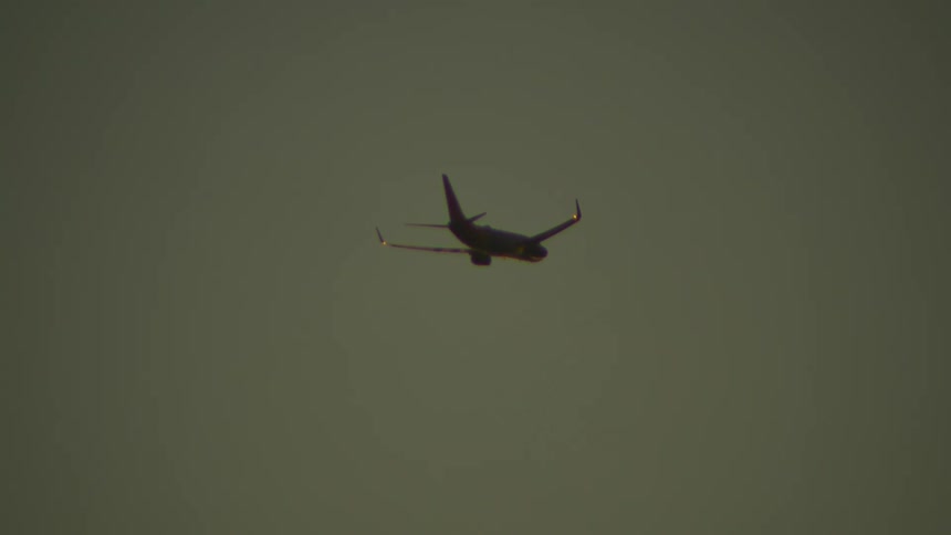 Airplane flying over a beach with sunrise on the horizon