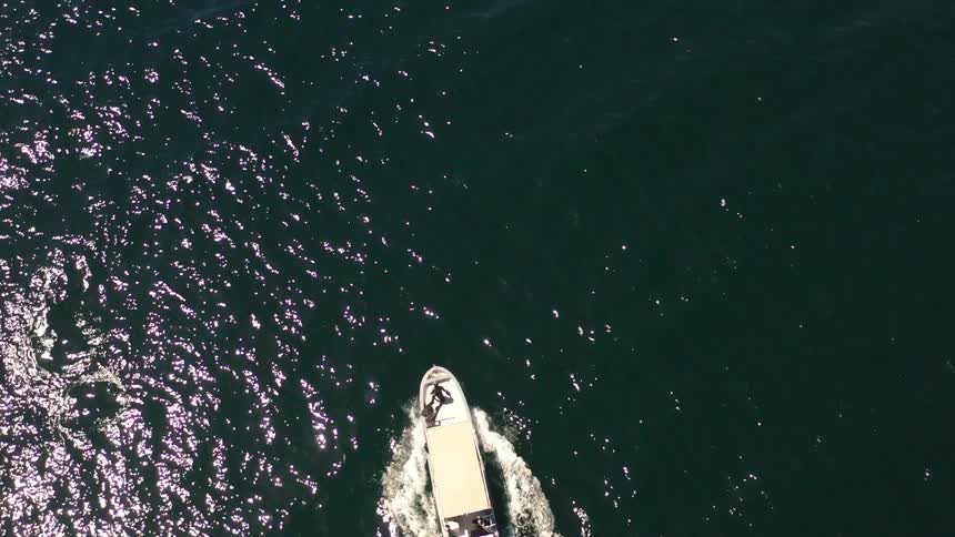 Top view of a speedboat moving through the sea with solar reflection