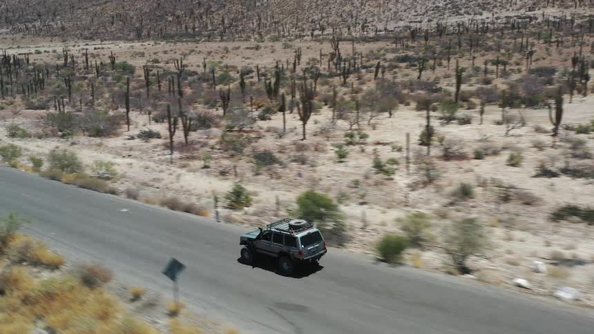 A vehicle drives down a road in a desert