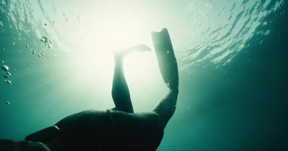 A man diving underwater with flippers on