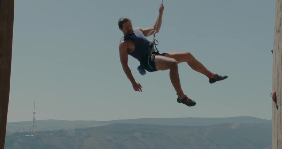 Man descending with a safety rope apparatus from a mountain