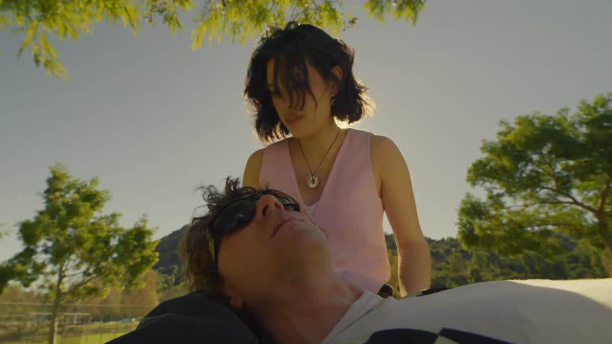 Couple with a woman sitting in the park and the man lying on her lap