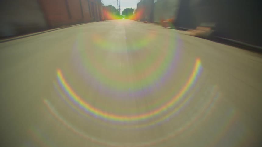The camera is going forward down a street very fast in a neighborhood