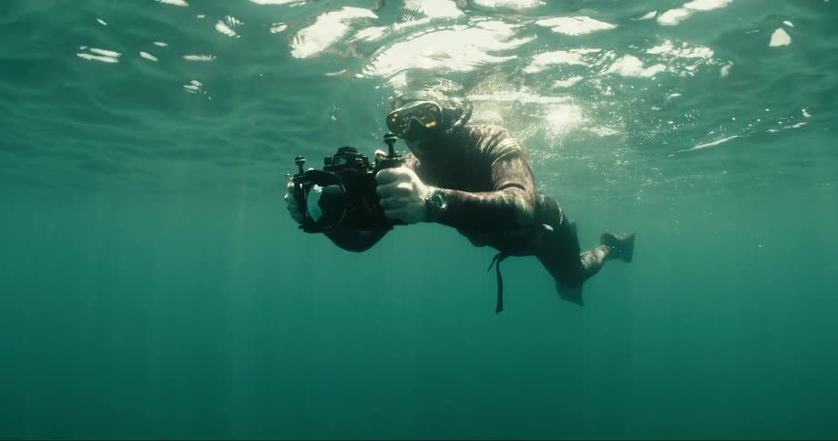 Diver near the surface swimming and holding an aquatic camera