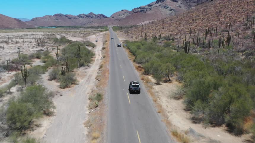 Some cars driving on an asphalt street in a desert region