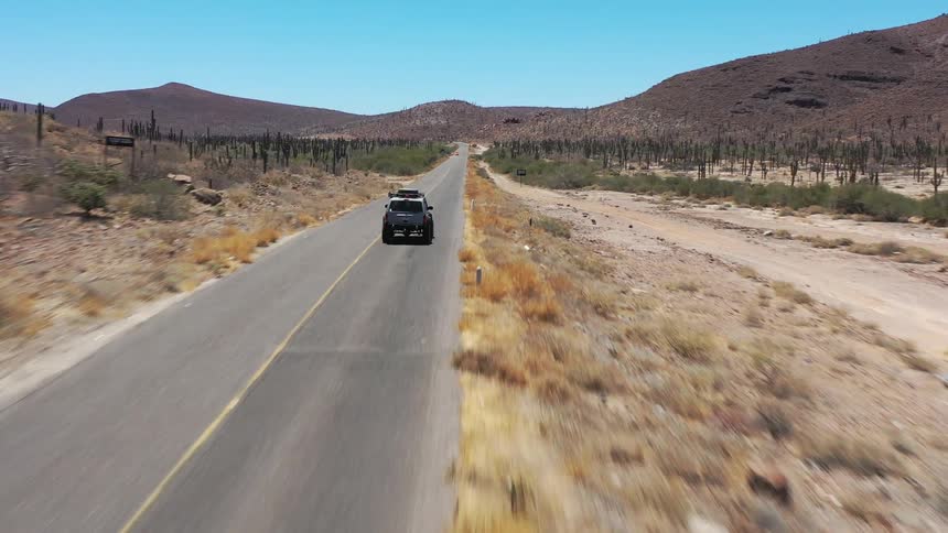Rally truck traveling along a street in an arid location with mountains around