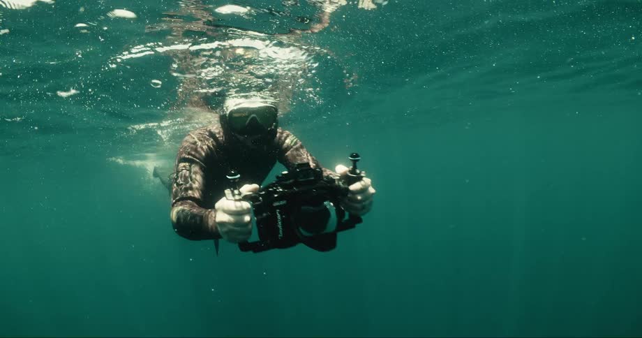 A person holding an object is diving and wearing breathing equipment