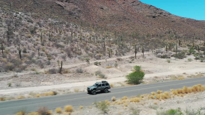 A vehicle travels down a road that runs through a desert