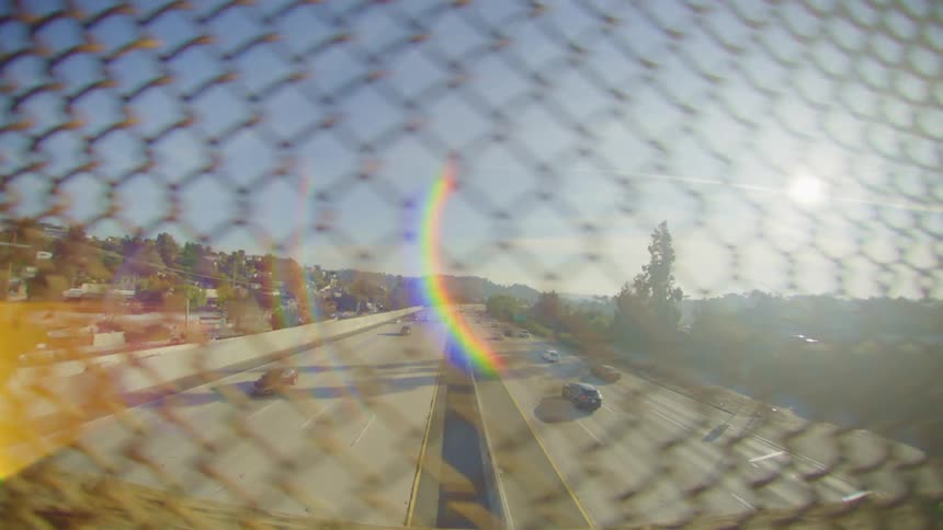 Traffic runs on the highway through the fence of the overpass