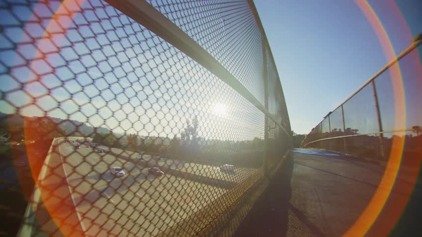 Top view of a viaduct protected by fences and vehicles passing over the highway
