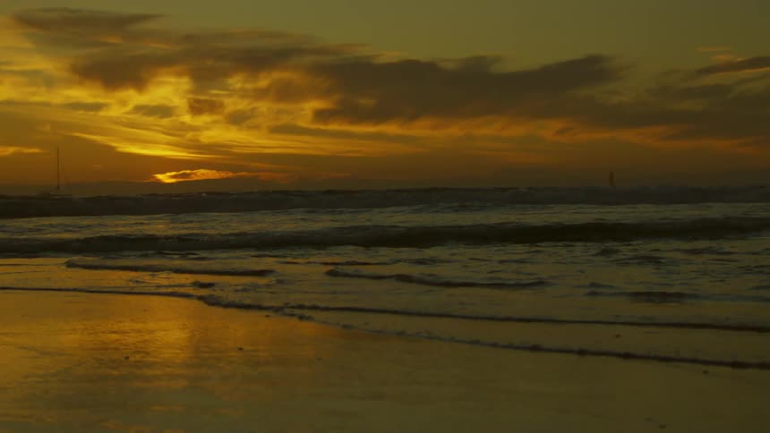 A view of the sunset over the beach with waves in the sea