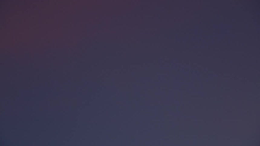 Crescent moon over beach at dusk