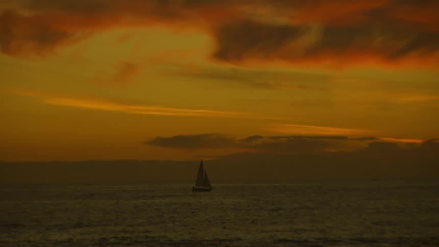 Ocean landscape with a boat on a day with orange dawn sky