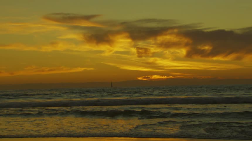 Paradisiacal panorama of a calm sea with light waves against the orange sky in the late afternoon