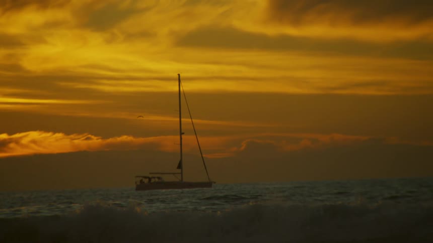 Boat in the midst of the sea in slow motion under a dawnpainted sky