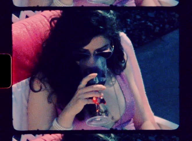 A woman drinking wine out by a pool on a sunny day
