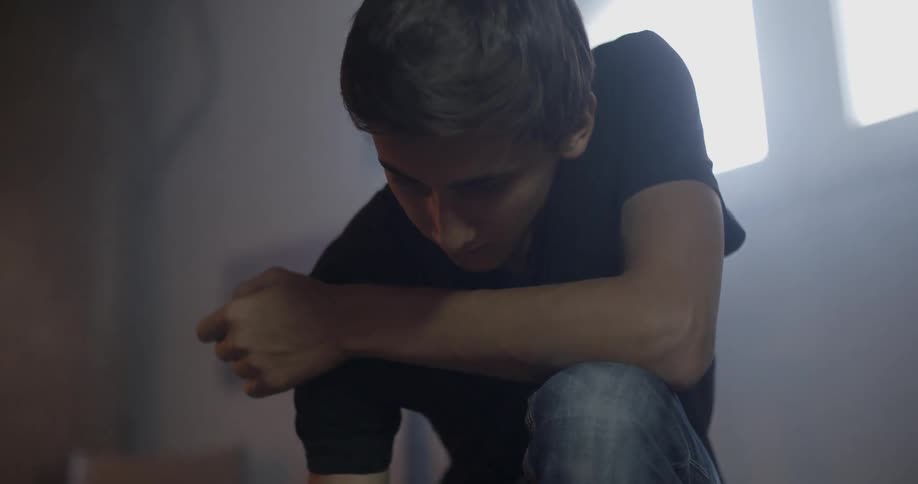A teenage boy is kneeling down and looking at something