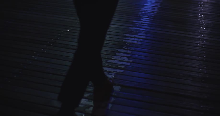 A person walks across a wooden surface as a blue light flashes