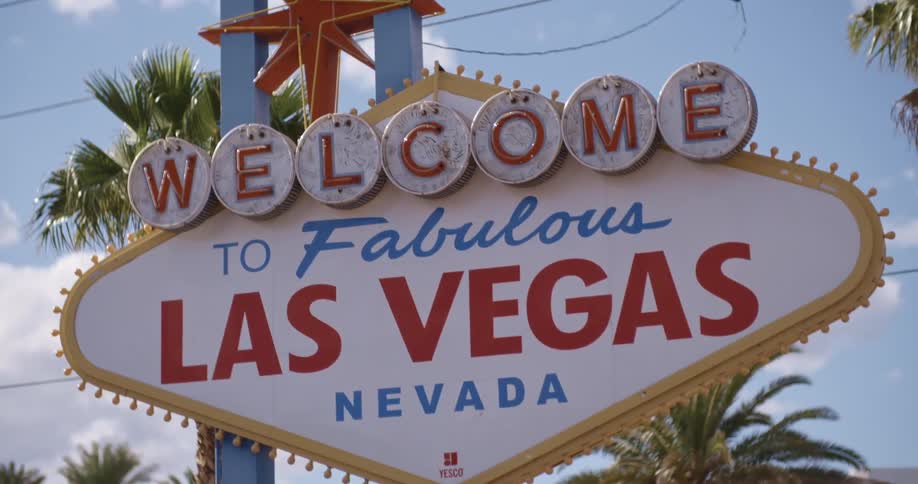 A 'welcome to las vegas' sign stand near power lines and palm trees