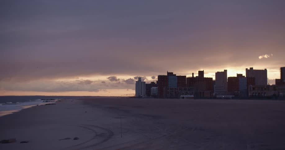 A beach with a city in the background at sunset