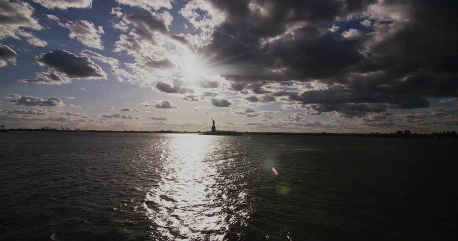 A bird flying over the water with the statue of liberty in the background
